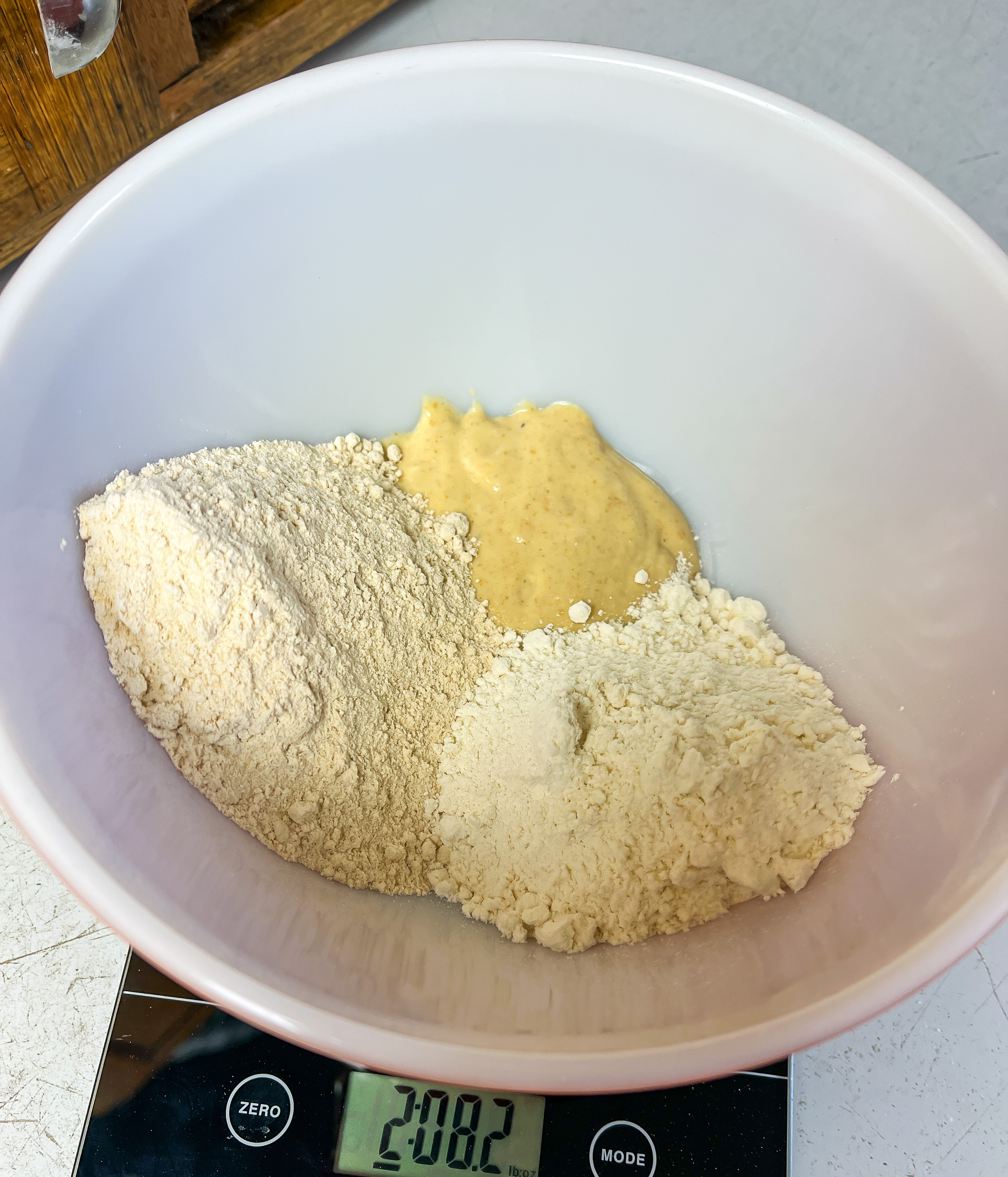 three piles of flour in a white bowl on a kitchen scale