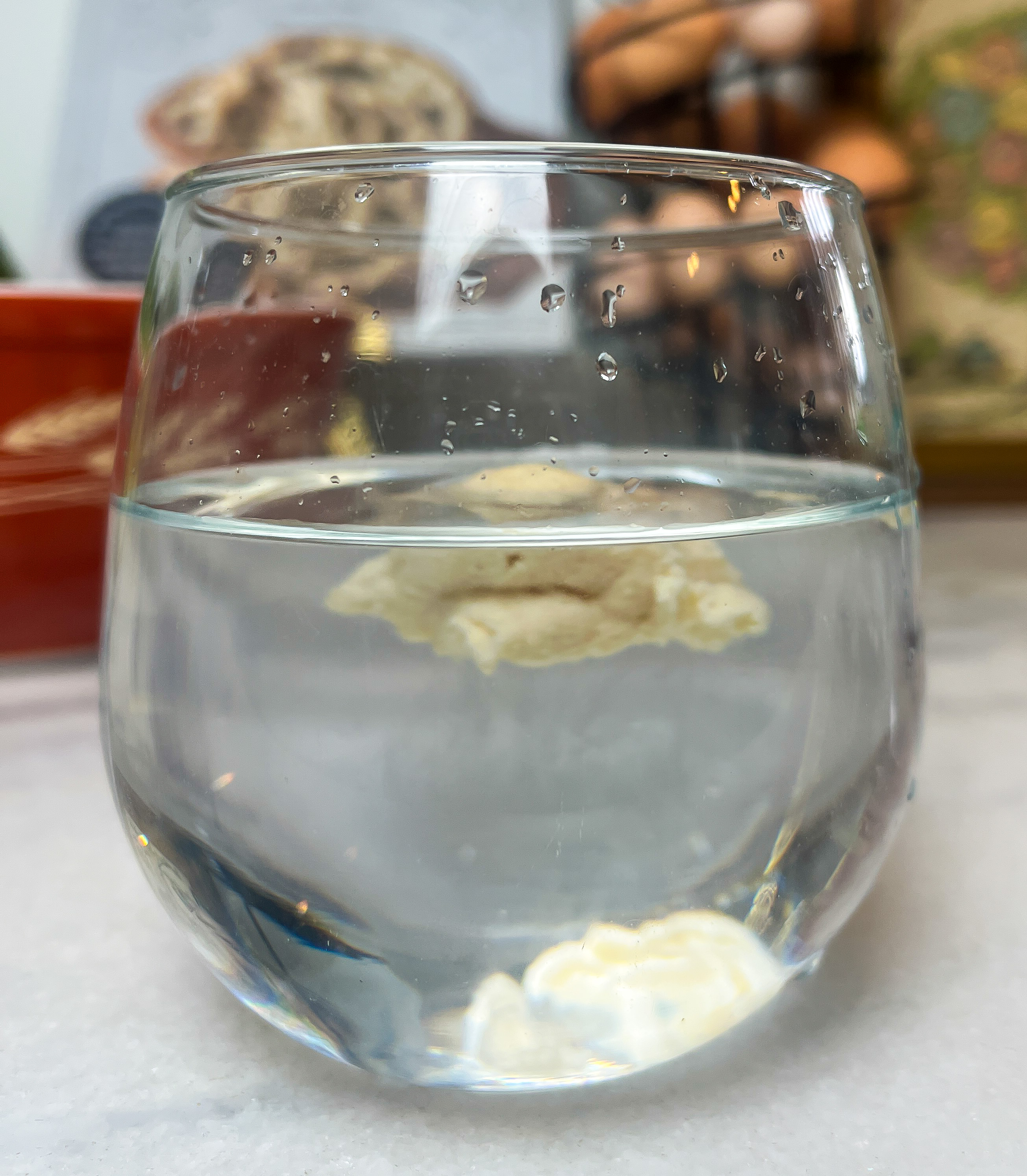 stemless wine glass with water and sourdough starter floating in the water